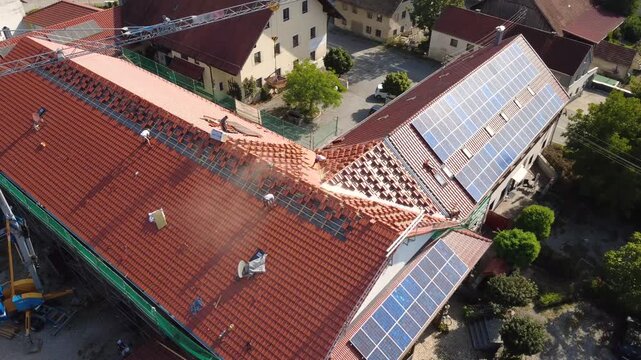 Aerial Orbit of Roofers Working on a Tiled Roof During Renovation with Solar Panels
