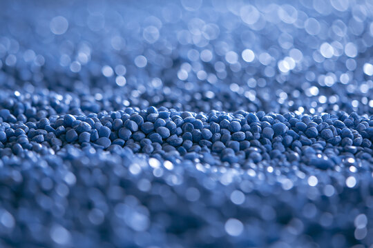 Macro shot of vivid blue plastic granules, symbolizing raw materials for industrial manufacturing, likely Polypropylene (PP) or Acrylonitrile Styrene Acrylate (ASA), with a sparkling,