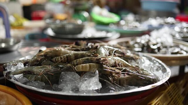 Close-up of fresh raw tiger prawns and seafood displayed on ice in a metal tray at Xom Moi Market in Nha Trang, Vietnam. Commercial food supply and retail trade concept.