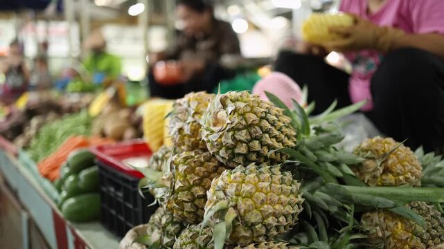 Close-up of fresh ripe whole pineapples stacked on a stall at Xom Moi Market in Nha Trang, Vietnam. Commercial food supply, tropical fruit market and retail trade concept.