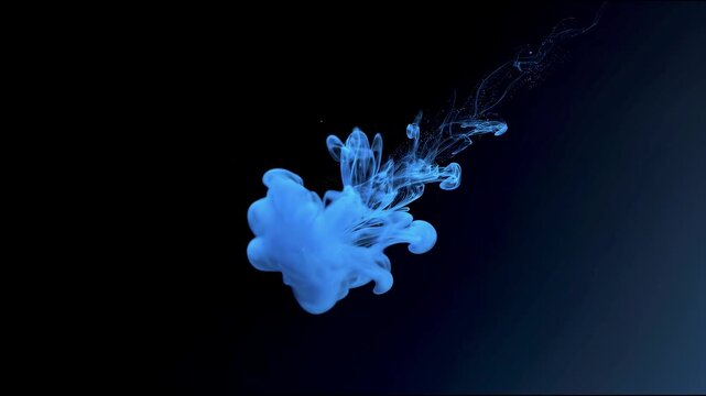 Abstract blue smoke and powder explosion swirling through darkness with glowing particles, fluid motion and dramatic high contrast on black background