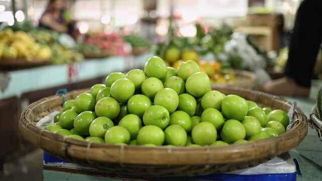 Close-up of fresh green jujube fruits displayed in a wicker basket on a stall at Xom Moi Market in Nha Trang, Vietnam. Commercial food supply and retail trade concept.
