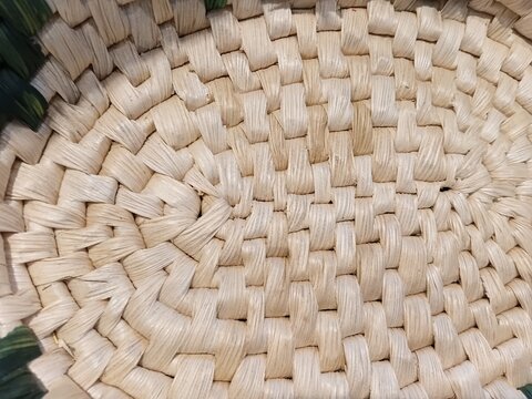 Texture of a woven basket made of light straw. Macro shot of a handmade craft piece made of natural materials