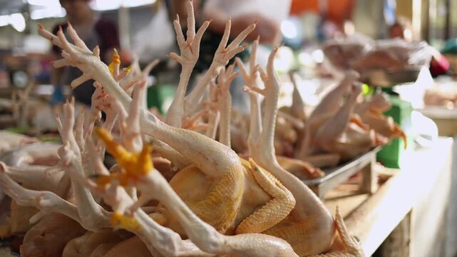 Close-up of fresh raw whole chicken carcasses with feet displayed on a stall at Xom Moi Market in Nha Trang, Vietnam. Commercial food supply, local poultry market and retail trade concept.