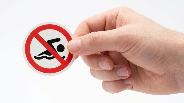 Hand holding a circular no swimming prohibition sign isolated on white background