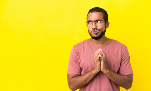 Young latin man isolated on yellow background scheming something