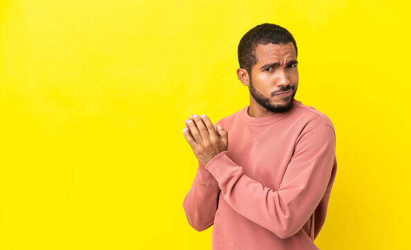 Young latin man isolated on yellow background scheming something