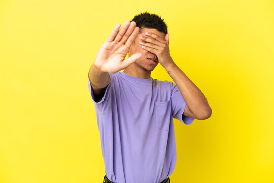 Young African American man isolated on yellow background making stop gesture and covering face