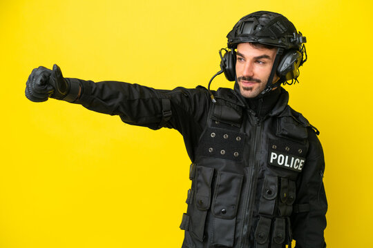 SWAT caucasian man isolated on yellow background giving a thumbs up gesture