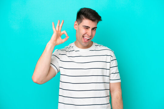 Young caucasian man isolated on blue background showing ok sign with fingers