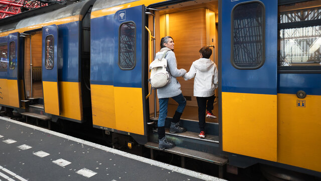 Mother and son boarding train at station platform