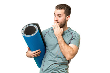 Young sport man going to yoga classes while holding a mat over isolated chroma key background with surprise and shocked facial expression © luismolinero
