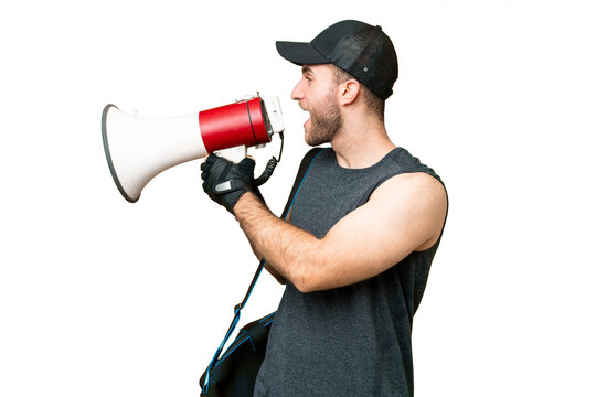 Young sport man with sport bag over isolated chroma key background shouting through a megaphone