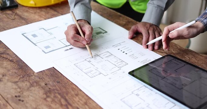 Architects and clients collaborate on property development, examining a house model and blueprints, planning residential construction and real estate projects together
