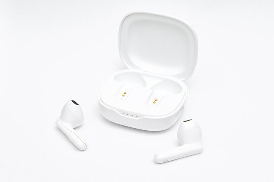 Wireless bluetooth earbuds set out of charging case on white background, product photography