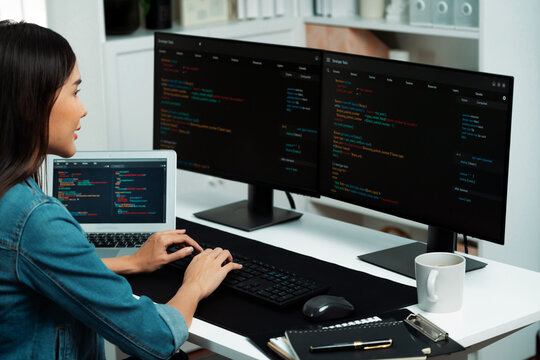 Young Asian in IT developer creating with typing online information on pc with coding program data of website application, wearing jeans shirt. surrounded by safety analysis two screens. Stratagem.