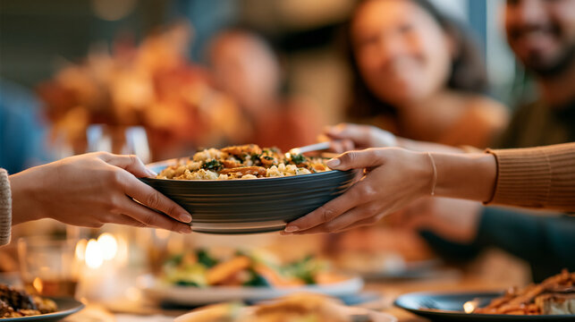 Candid medium shot of hands passing a bowl of mashed potatoes around a crowded harvest dinner table, warm evening candlelight mixed with practical interior lighting, moderate depth