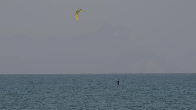 Kitesurfing over the Tyrrhenian Sea at Marina di Latina, Italy, during a bright summer day