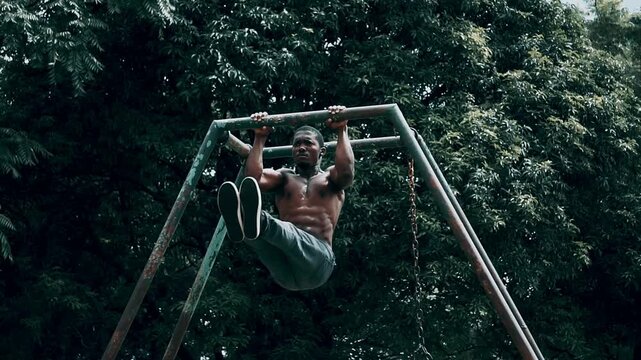Muscular African man performing a hanging L-sit pull-ups, outdoors on a metal frame, showcasing intense core strength. Young Zambian youth doing Pull ups in a park.