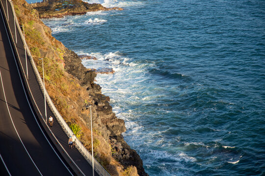 Persone che passeggiano su strada accanto a lungomare roccioso