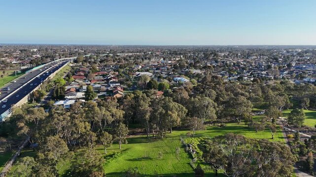 Aerial view of the Princes Freeway running alongside green parkland reserves and residential neighborhood housing in Laverton, Melbourne, Australia.