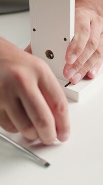 Close up of a man in slow motion assembling furniture parts together indoors, connecting components during a DIY home project