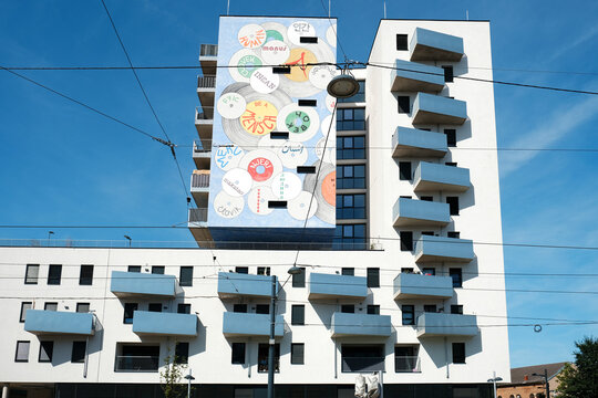 Vienna, Austria - August 24, 2025: Modern residential building facade with large mural artwork and blue balconies. 
