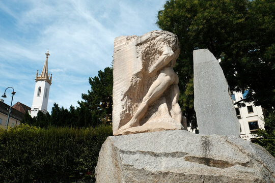 Vienna, Austria - August 18, 2025. Low angle view of the Monument Against War and Fascism by Alfred Hrdlicka, with the Augustinerkirche church spire in the background.