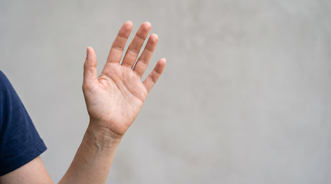 Close up of a human hand making a friendly waving gesture against a neutral background with copy space, representing greeting, hello, welcome, communication and farewell.