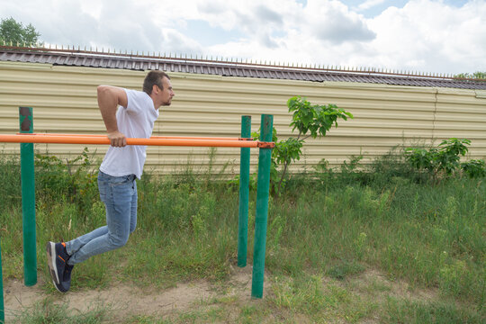 Man doing triceps dips on parallel bars at sport ground