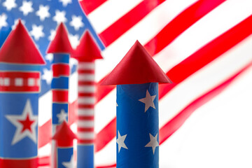 Obraz premium Fourth of July USA Independence Day festive celebration concept with copy space. Handmade craft paper rockets decorated with stars and stripes, clapper and confetti, white background.