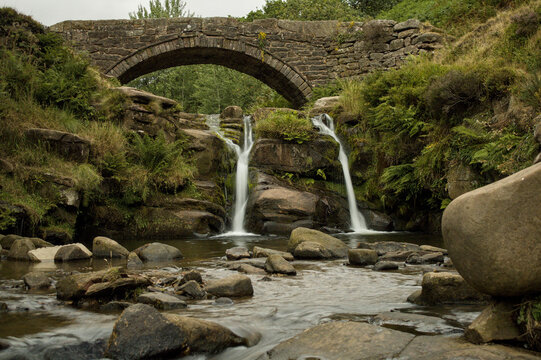 Small Waterfall Flowing Beneath a Stone Bridge
