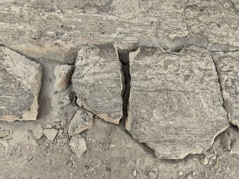 Broken and cracked concrete pavement texture background, destroyed cement road surface close up