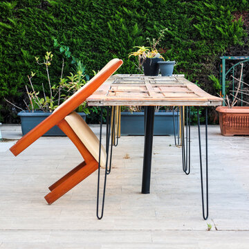 Urban street scene with wooden chair balanced on two legs leaning against a table, unusual outdoor furniture arrangement in the city.