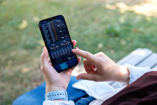 Woman points with the finger on the smart phone screen, stock chart and market data. Investment decision, strategy, stock prices, financial advisor, assets, growth, wealth, online trading.