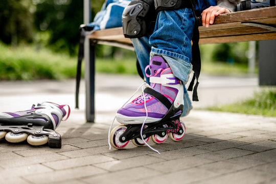 Young skater adjusts purple inline skate on park bench