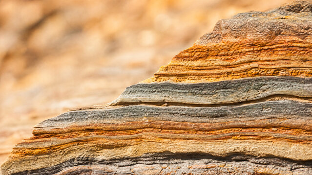 Layered rock sediment strata cross section with warm colored bands revealing geological history