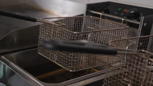 A detailed view of the empty deep fryers in the commercial kitchen of a fast-food establishment. Two empty fryers, one for French fries and the other for chicken nuggets.