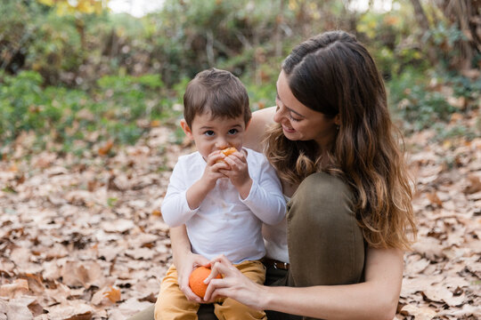 Mother and child enjoying sweet tangerines in autumn