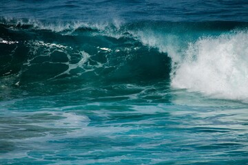 Naklejka premium Powerful ocean wave breaking with white foam and turbulent turquoise water in open sea.