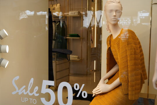 Fashion Mannequin Wearing Mustard Knit Outfit Behind Store Window Sale