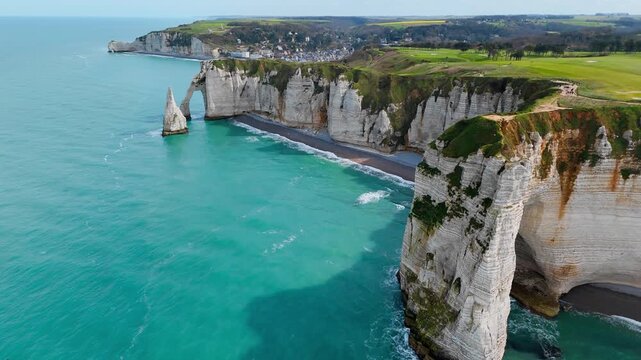 Aerial drone footage of coastal limestone cliffs near Etretat, France. English Channel shoreline with natural arch, sea stack and rocky coast