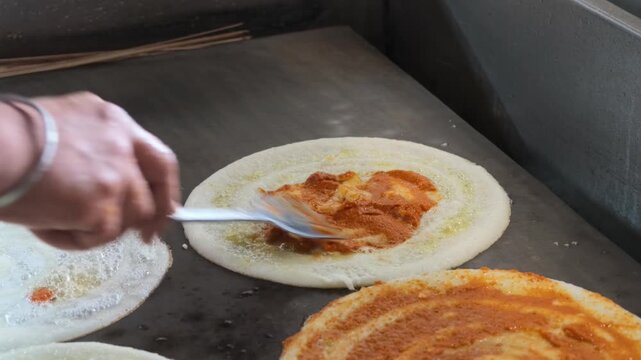 Traditional benne masala dosa being prepared on hot griddle close up