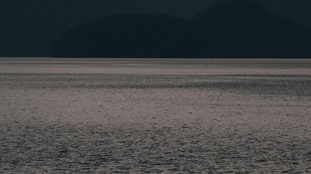 Gray ripples on Lake Toya with a dark blue island silhouette
