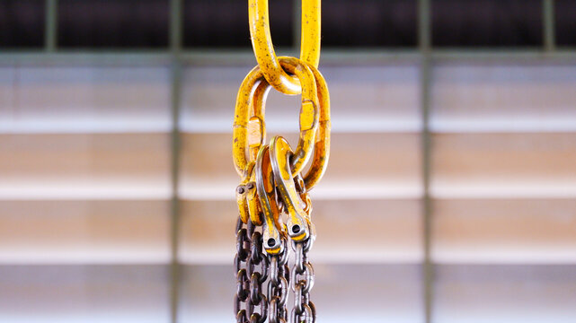 Lifting hooks and chains used in the production process. The hooks are suspended from chains above the work area and are used for lifting and moving heavy workpieces or materials.