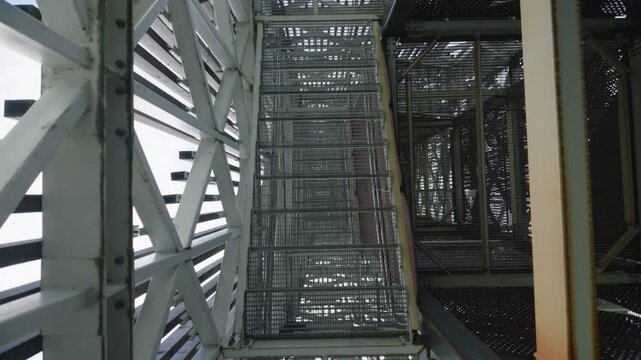 Camera looking down metal staircase inside industrial tower structure