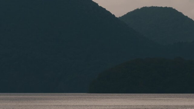 Gray ripples on Lake Toya with a dark blue island silhouette
