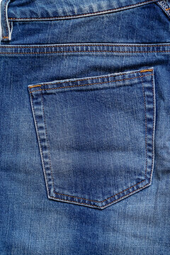 Detailed denim back pocket showcasing precise stitching and the rich texture of woven blue fabric.