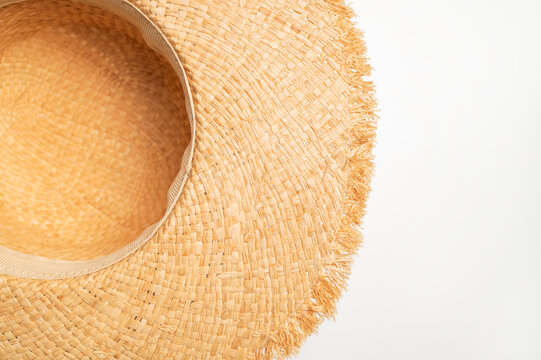 Womens straw hat on white background top view with space for text. Stylish beach hat with wide brim, fashionable summer accessory for vacations and sea.