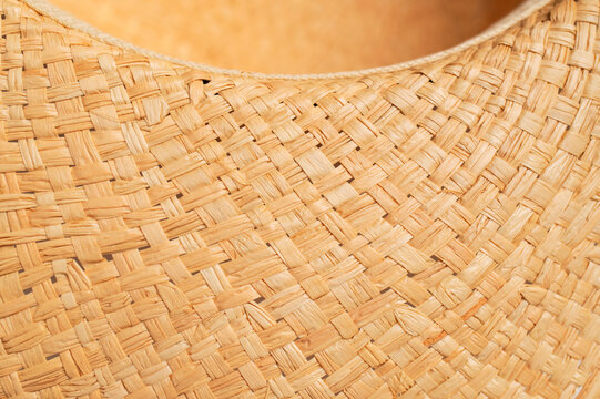 Close-up of woven natural straw texture shows detailed interlaced fibers in warm beige tones. Woven surface and braided material create useful background for summer, craft and eco design projects.